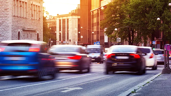 Cars driving down a main road of a city at sunset