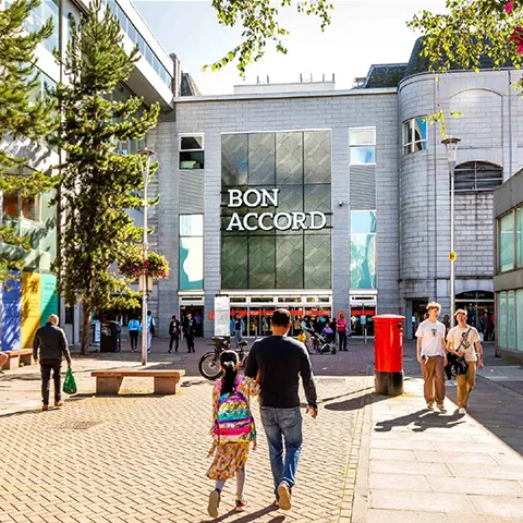 Main entrance of the Bon Accord Shopping Centre with people entering the centre