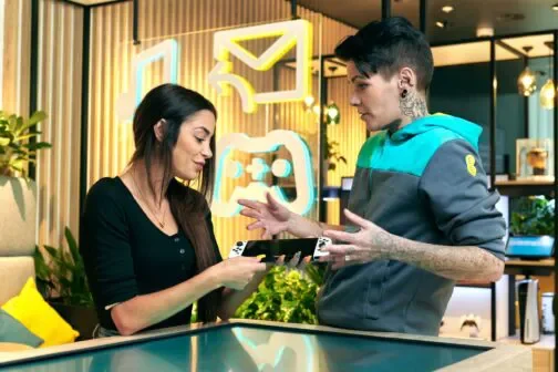 EE customer holding Nintendo Switch while talking to an EE employee.